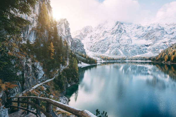Nature in South Tyrol: Deep blue mountain lake, surrounded by snow-covered mountains and forests