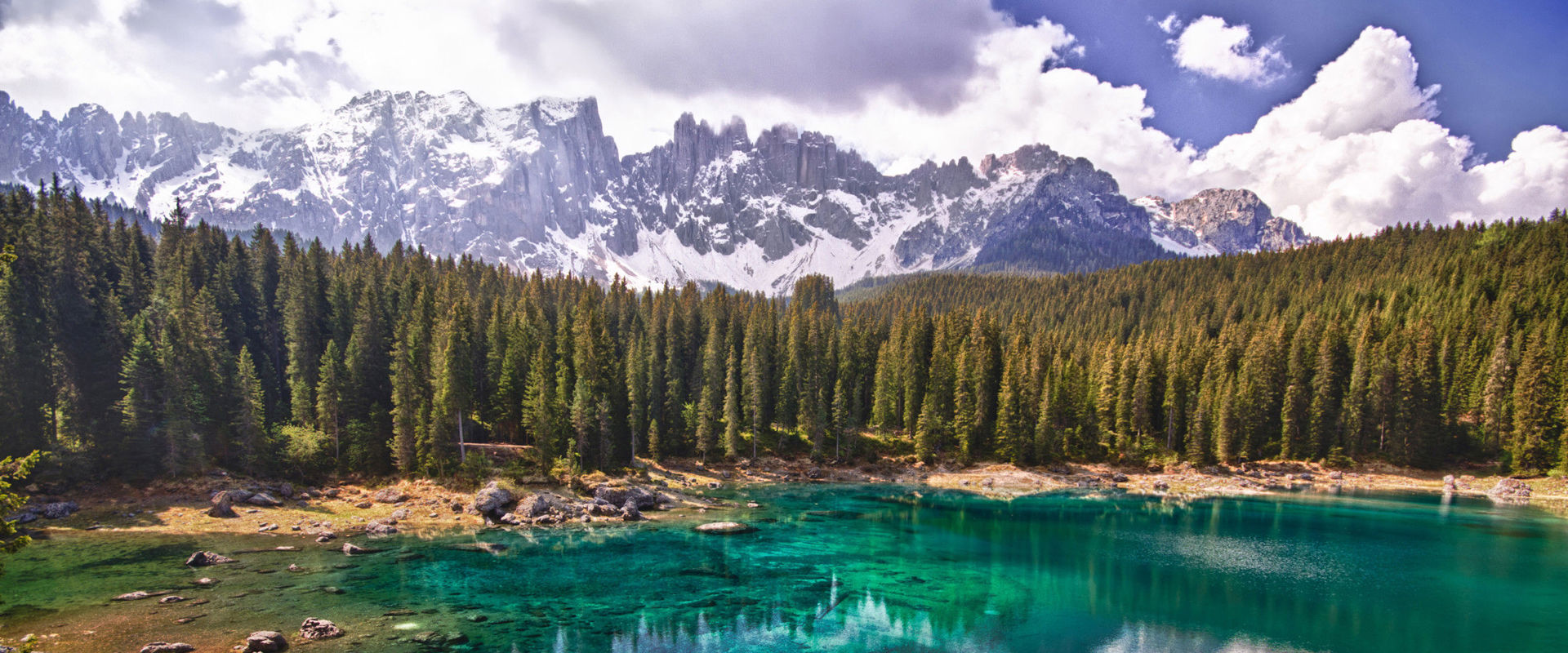 Lake Karersee Turquoise mountain lake framed by dense coniferous forests and rocky mountain peaks.
