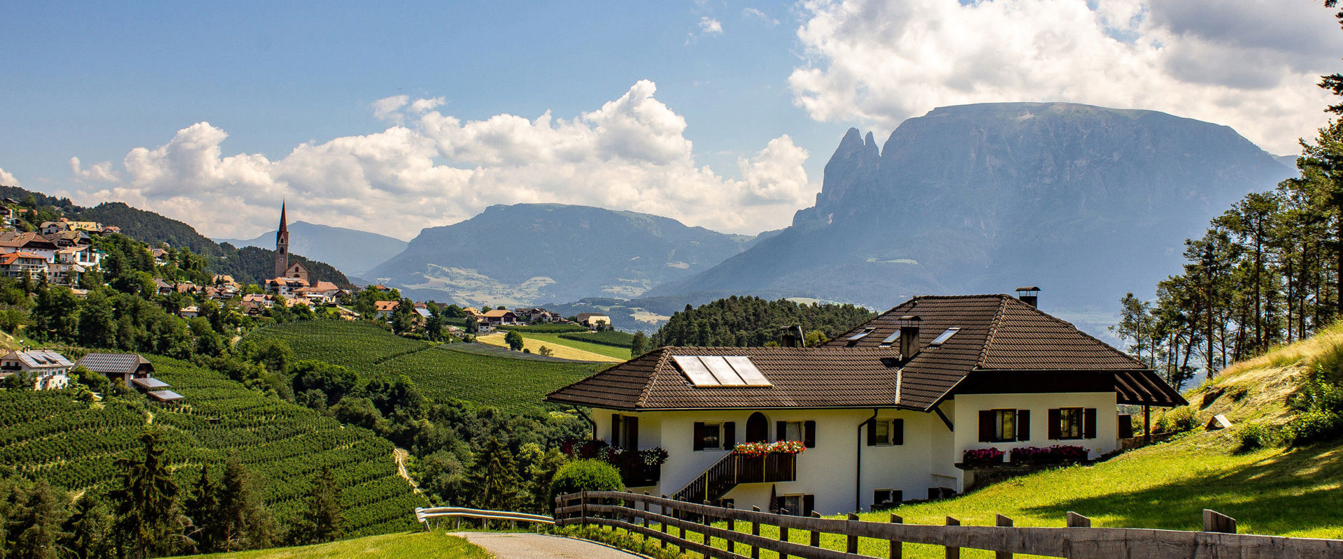 Ritten Road with house on the Ritten, past meadows and vineyards with church and Schlern in the background