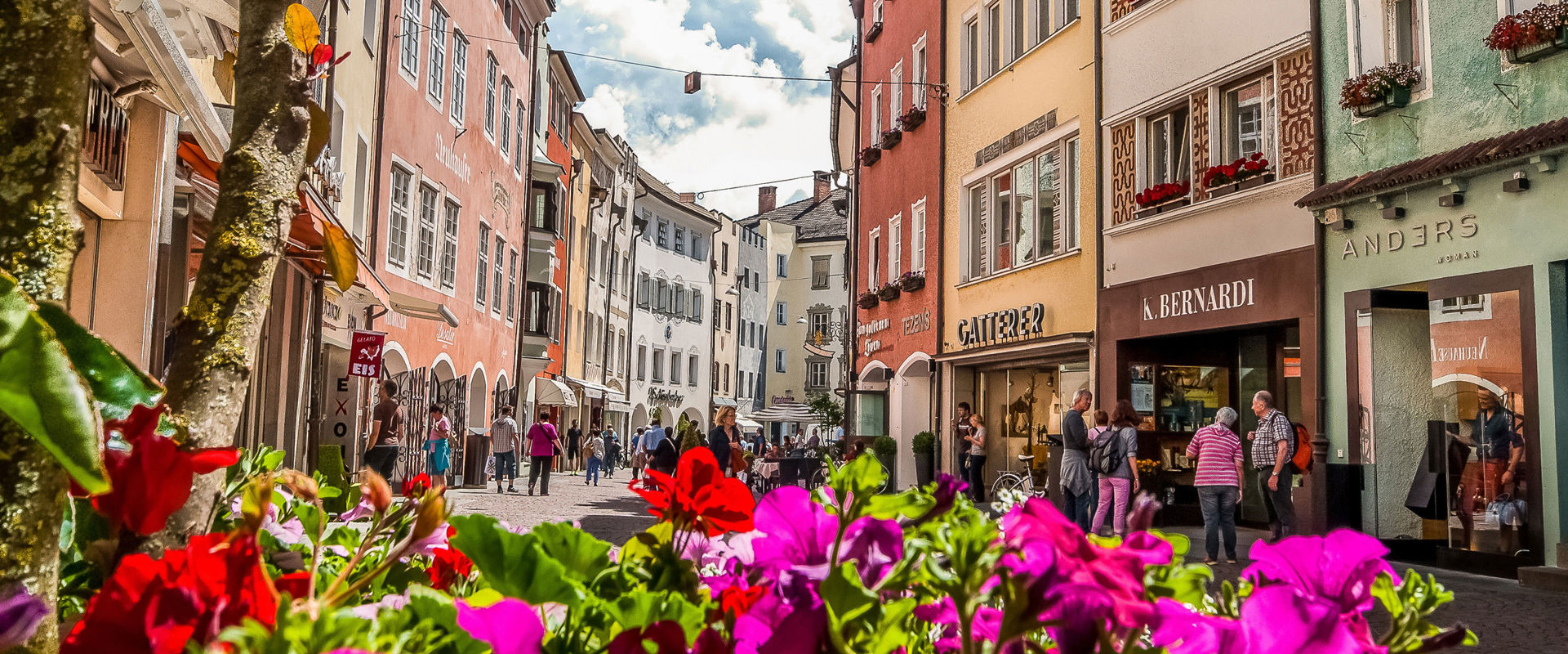 City trip to South Tyrol in summer. Lively city centre with colourful house facades framed by bright summer flowers.