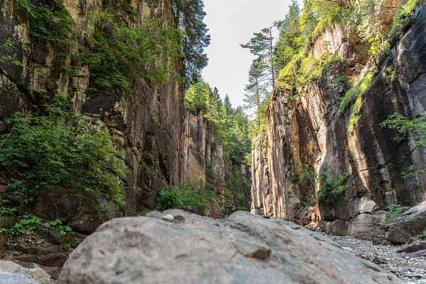 To the left and right of the picture, you can see reddish, steeply rising rock faces overgrown with a few trees.