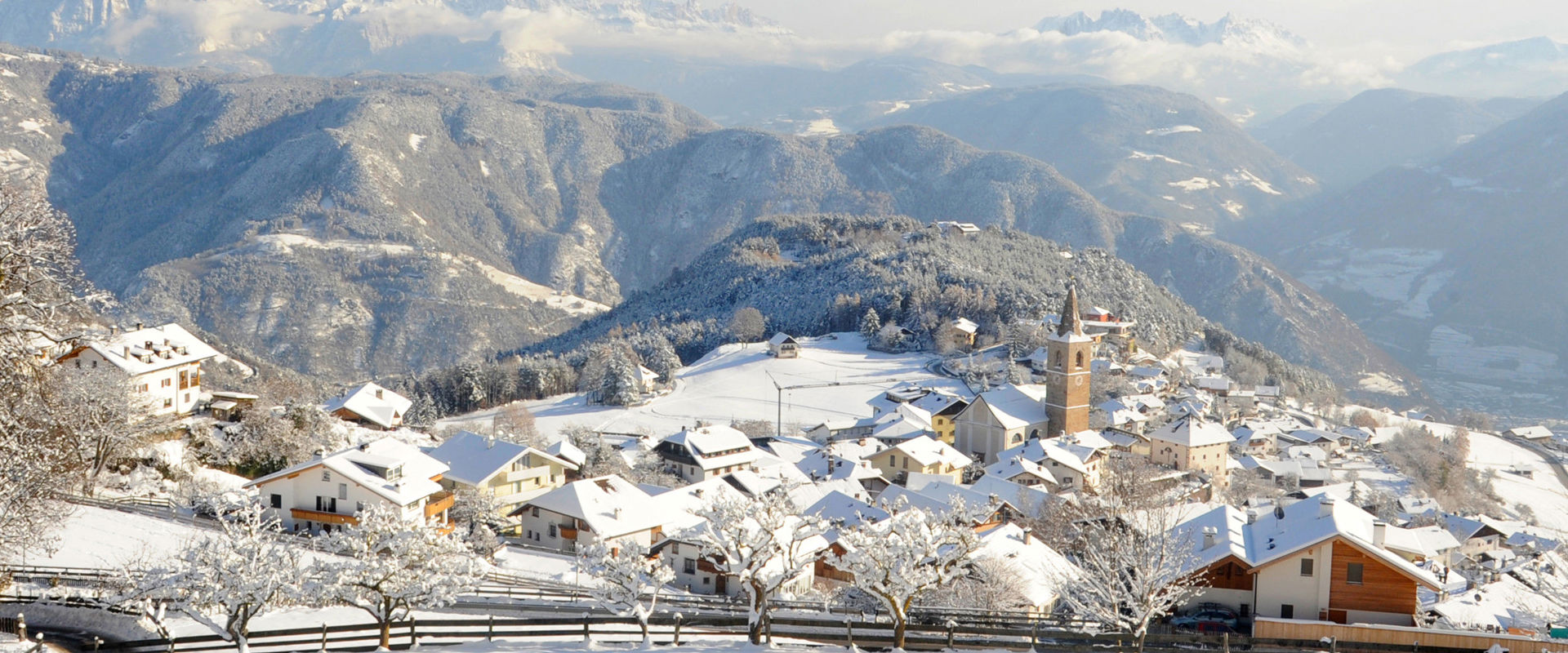 Jenesien Jenesien from above in winter with village centre and church, Dolomites in the background