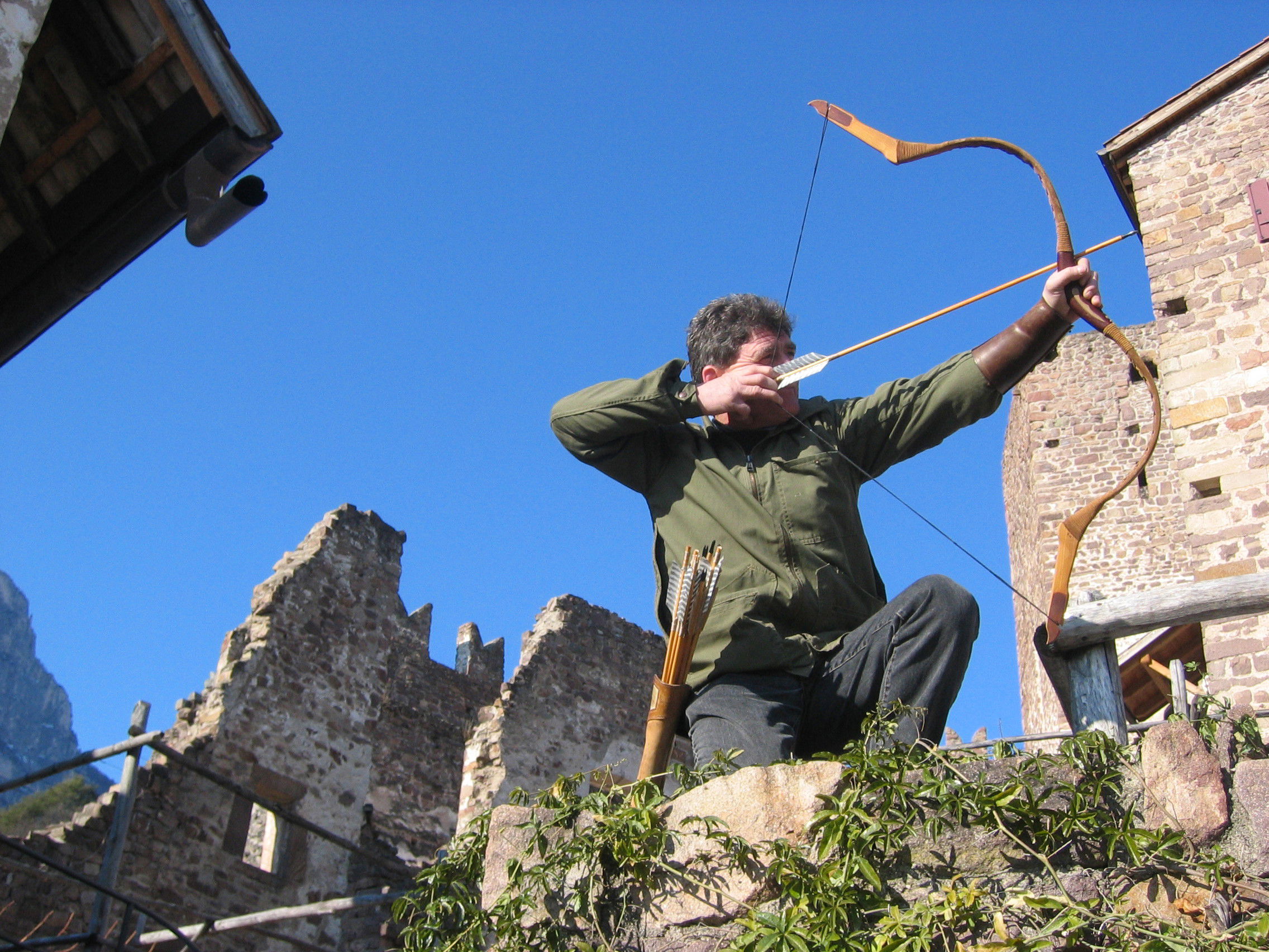 Man aiming his bow at the castle ruins.