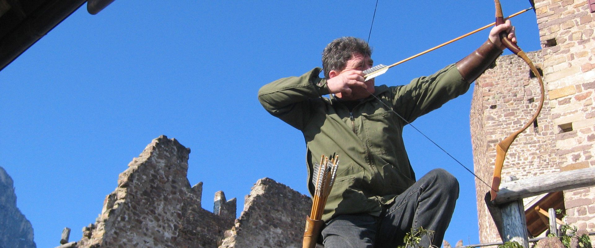 Archery course near Hocheppan Castle. Man aiming his bow at the castle ruins.