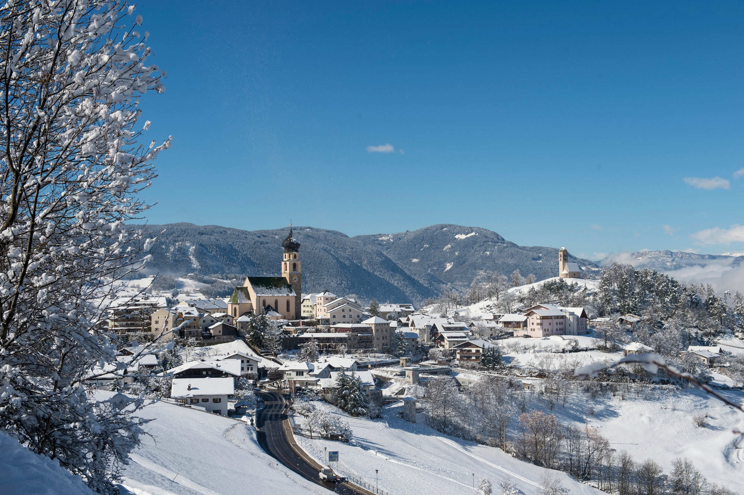 The mountain village of Völs am Schlern amidst a white wintry landscape.