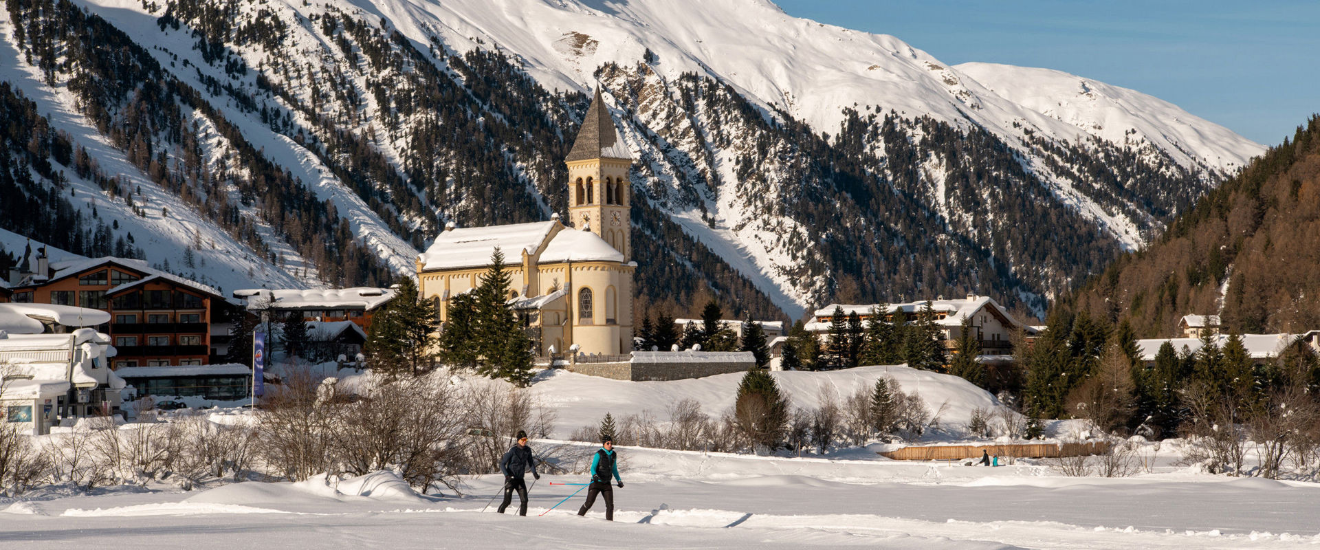 Two cross-country skiers on the trail right next to the village of Sulden.
