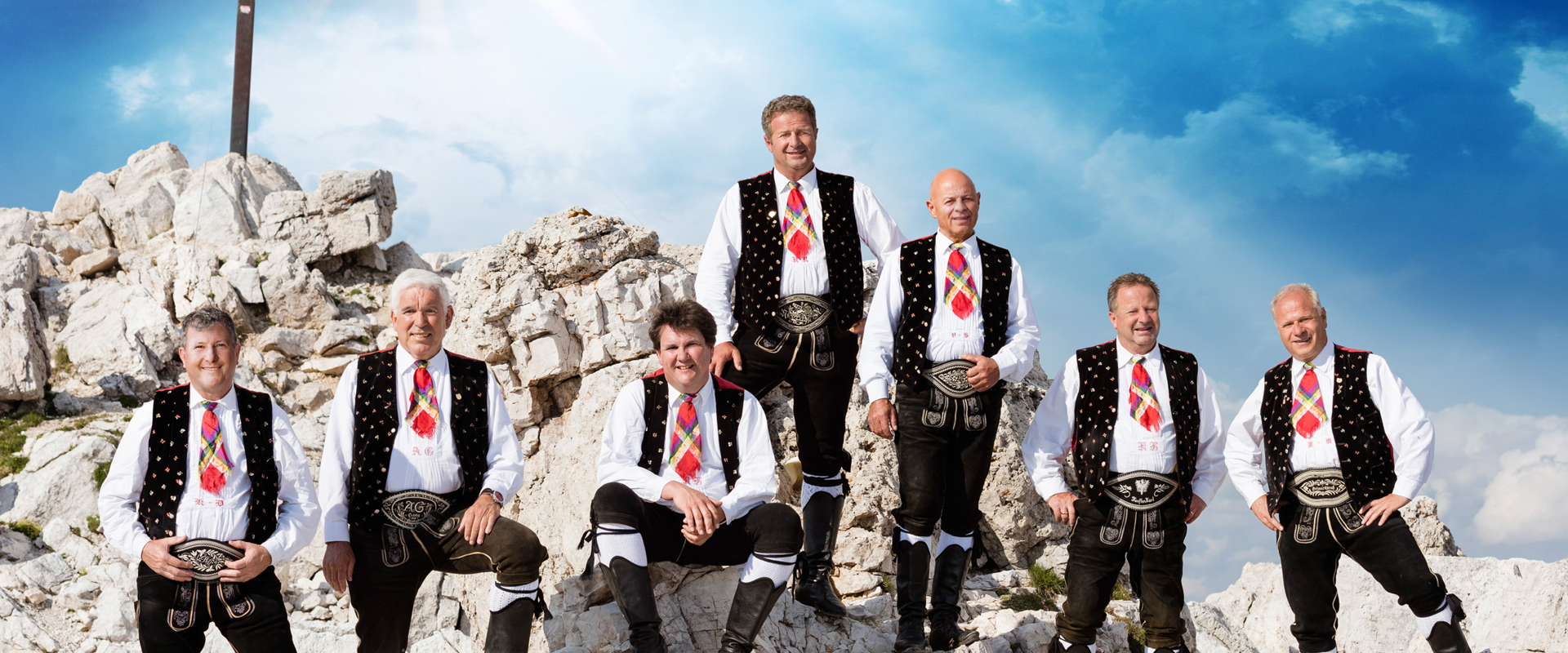 Kastelruther Spatzen Music band standing in front of the summit cross.