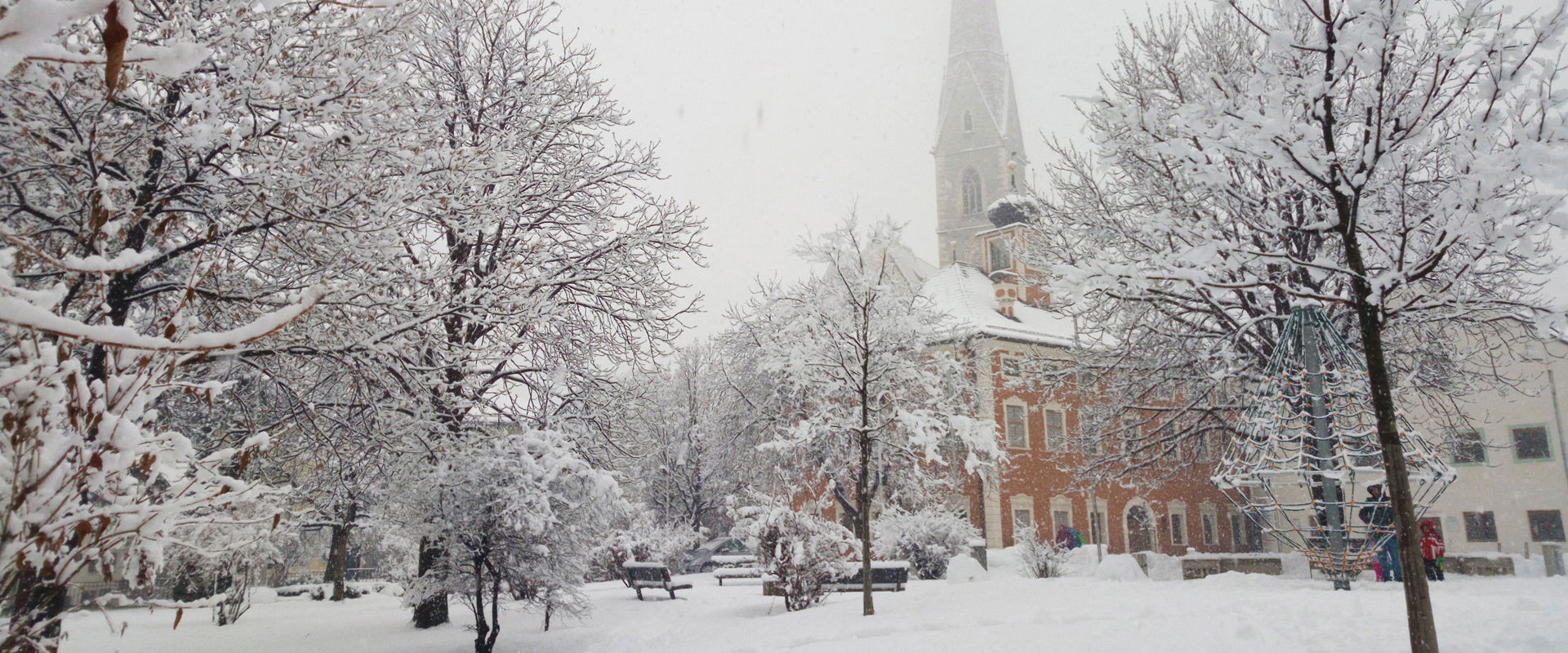 Parish church Maria Himmelfahrt in winter. The Church of the Assumption and the park are covered in snow.