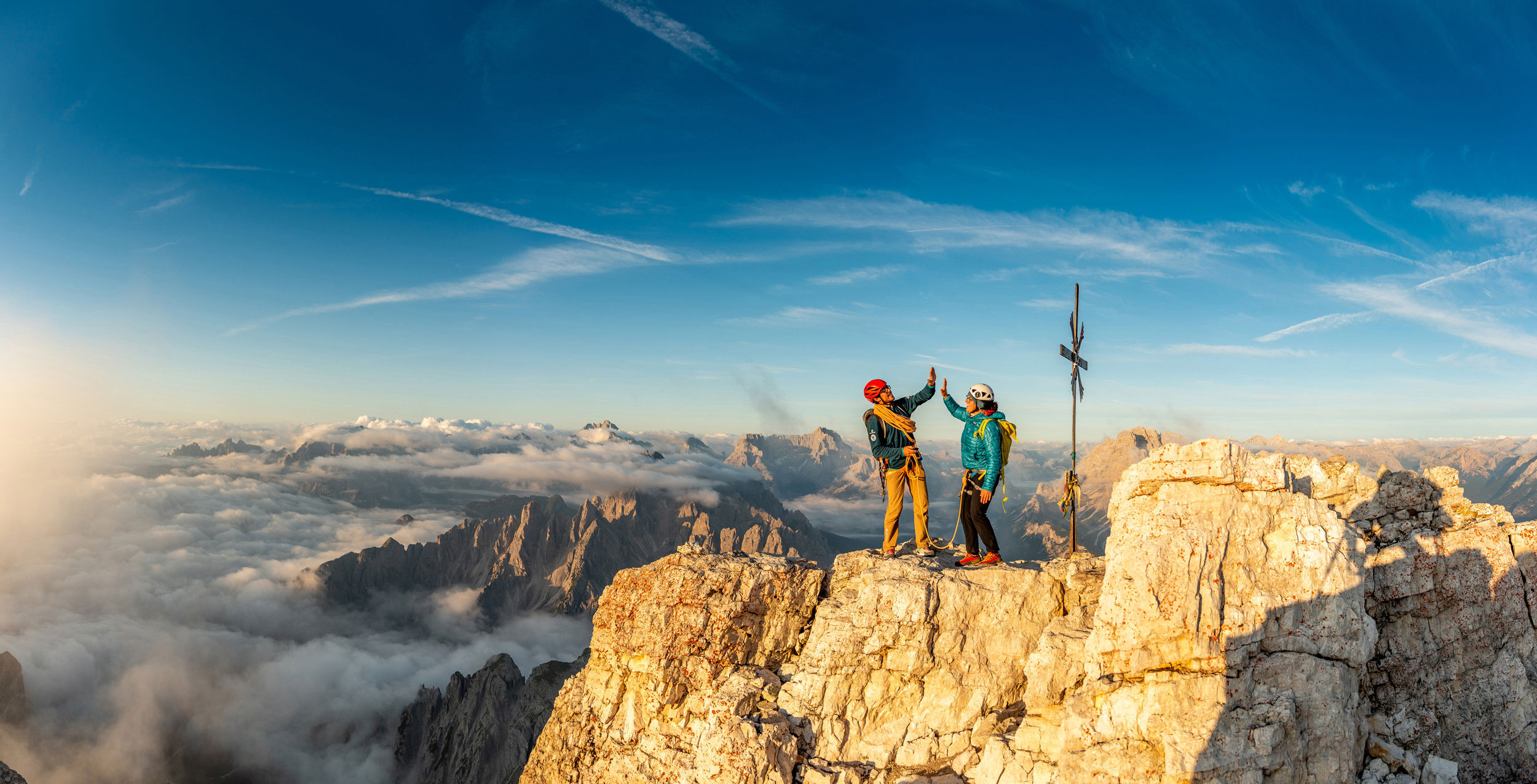 Two climbers celebrate their arrival at the summit cross.