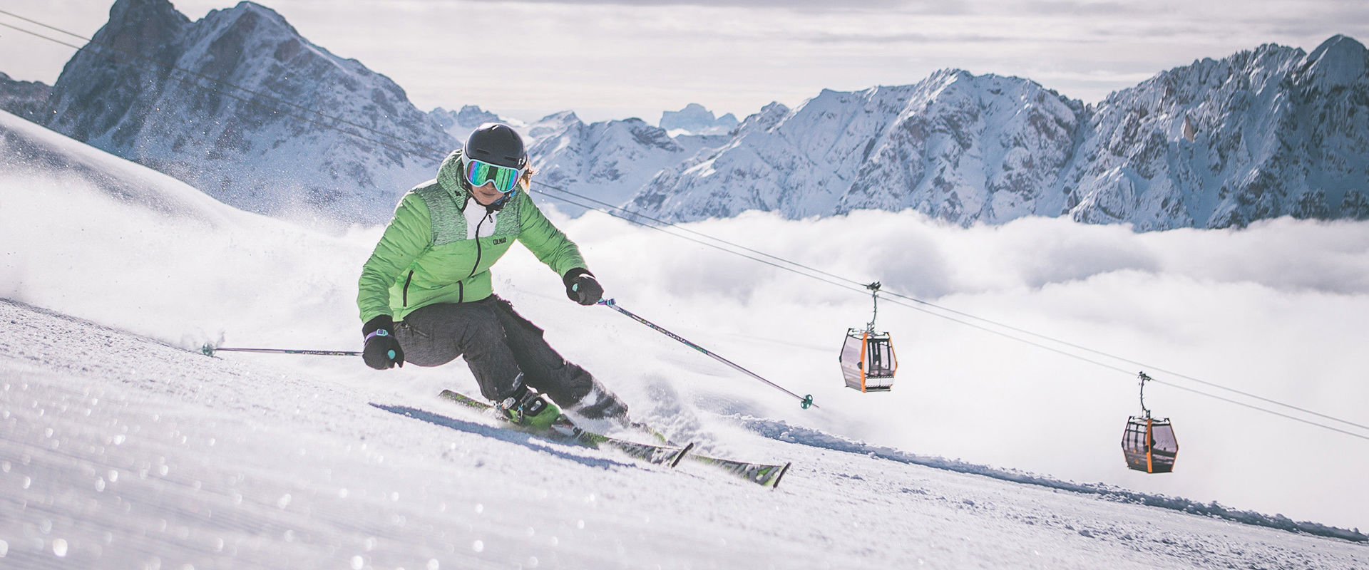 Ski area Plose Skier goes down the slope. In the background one can see the gondola and the snow-covered mountain peaks.