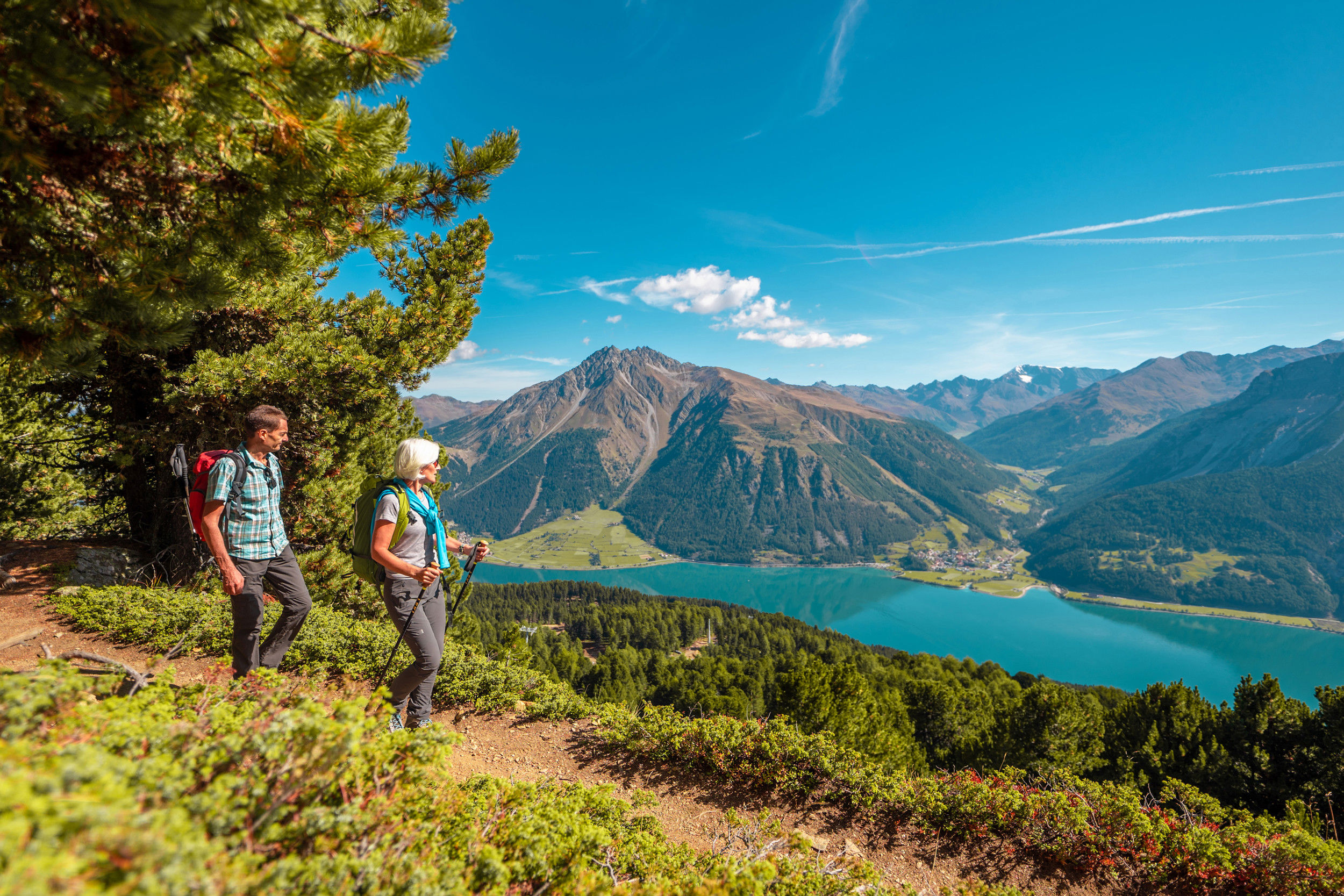 Two hikers look down on Lake Reschen and the mountain landscape