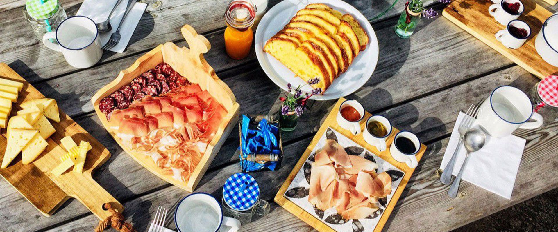 Breakfast table with delicious breads, cold cuts, cakes, drinks and jams.