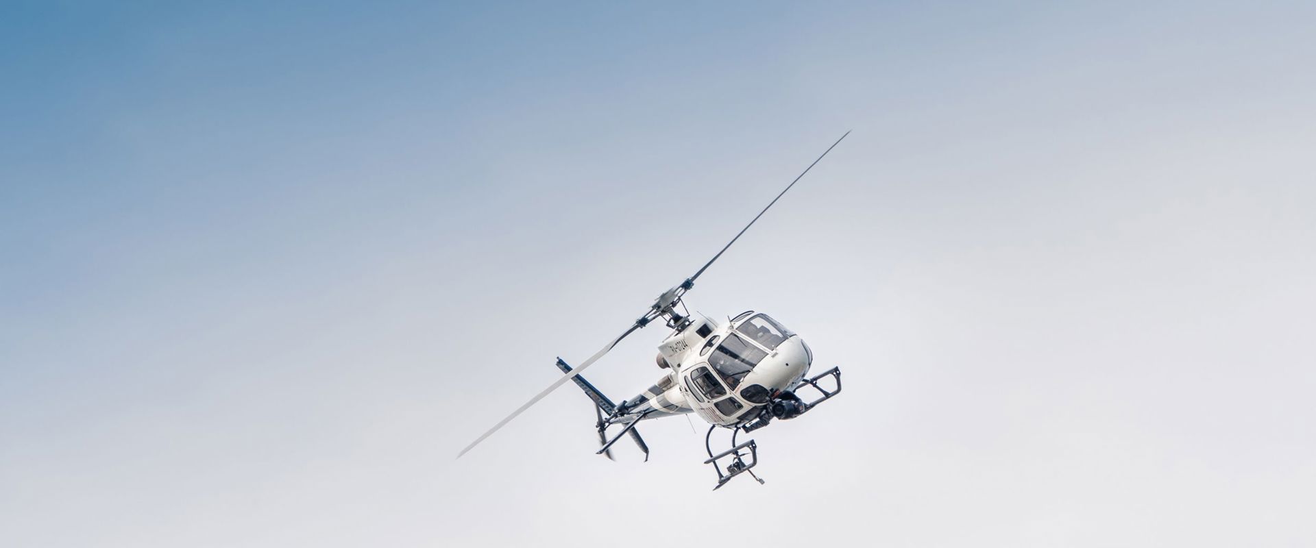 Helicopter sightseeing flight A white helicopter flies in the air.