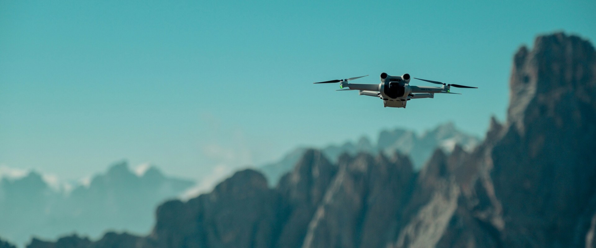 Drone hovers in front of mountain peaks