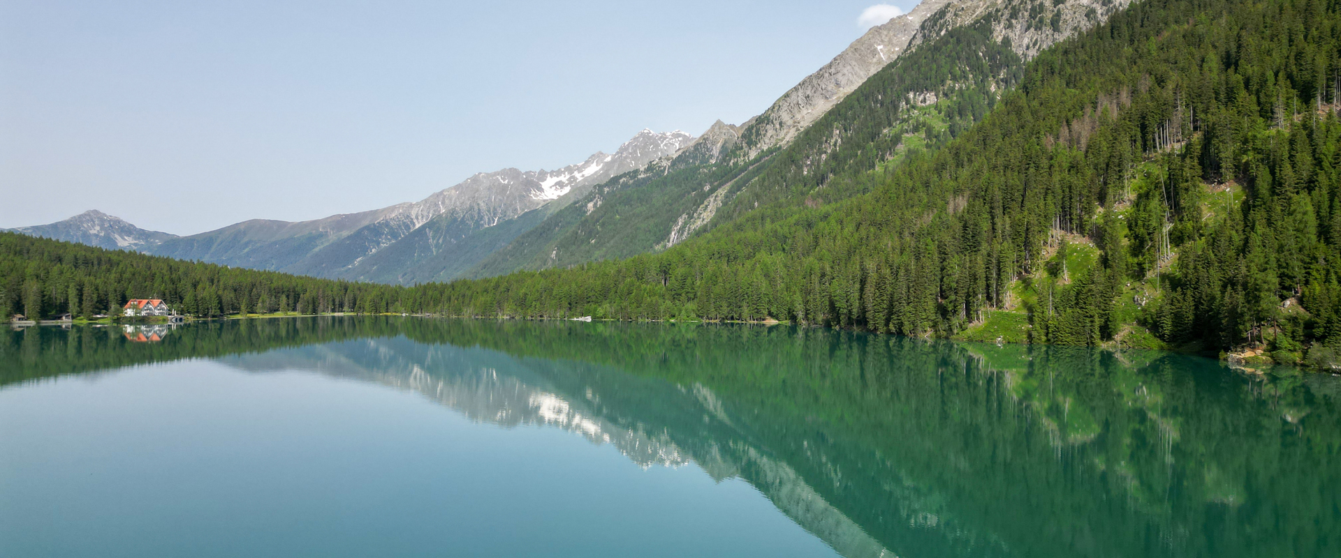Green-blue mountain lake (Lake Antholz) surrounded by dense forest