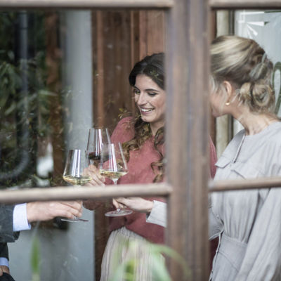 Three friends drink a glass of white wine by the window in a bar.