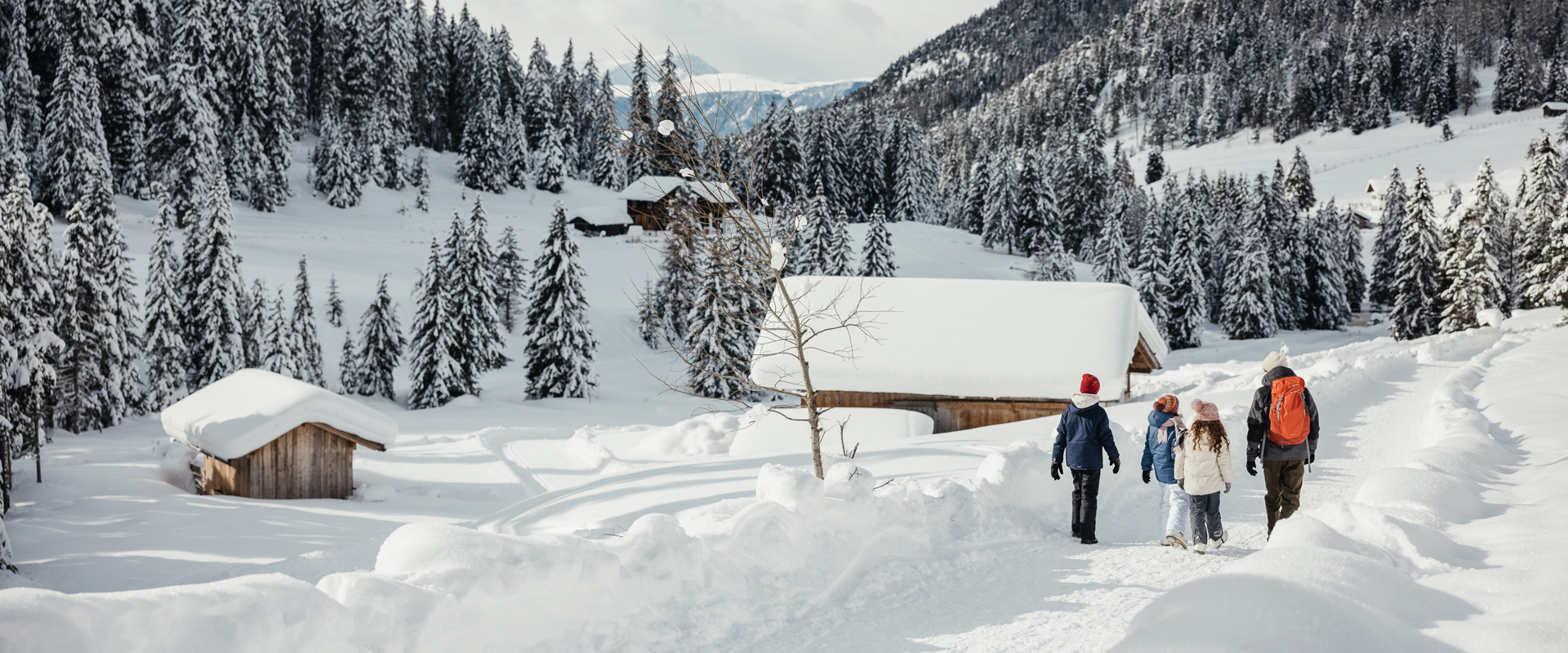 Winter hike Family hiking on a winter hiking trail through a snowy landscape with mountain huts.