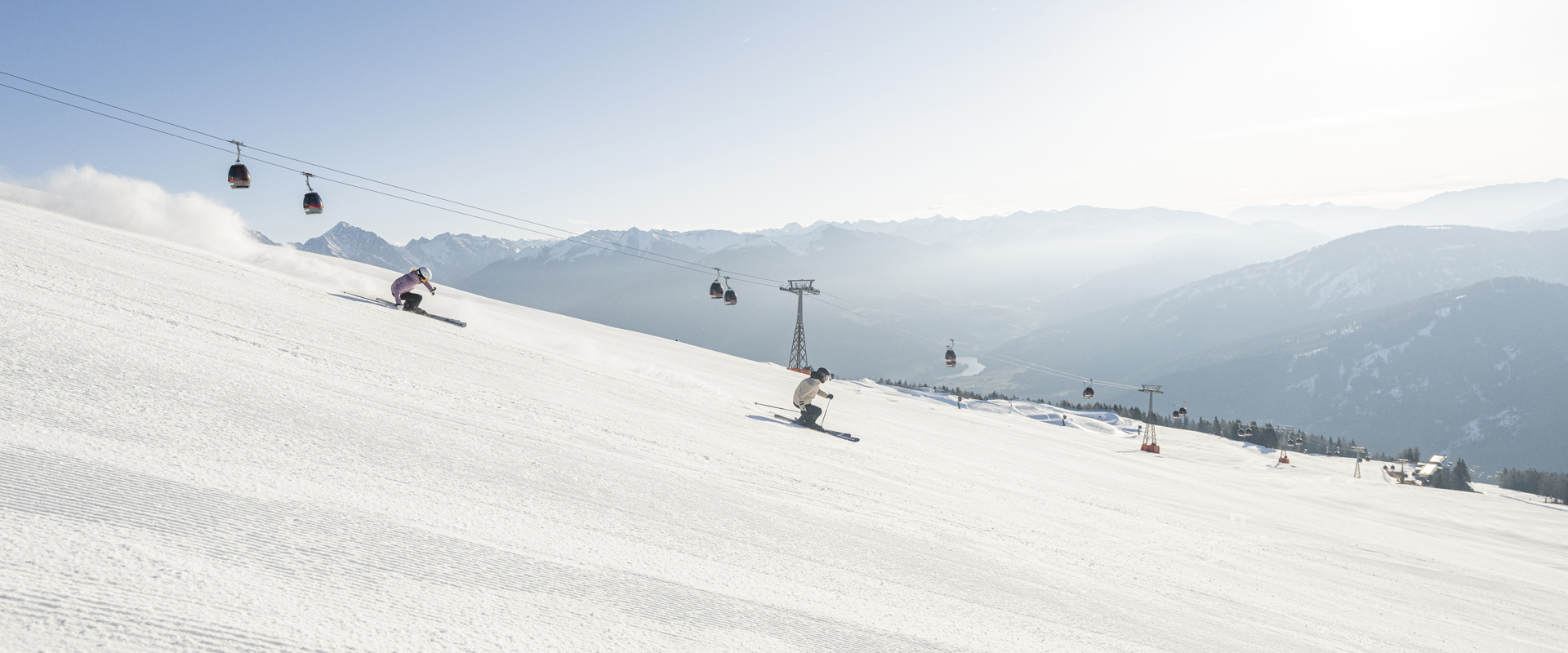 2 skiers ski over the freshly prepared ski slope.